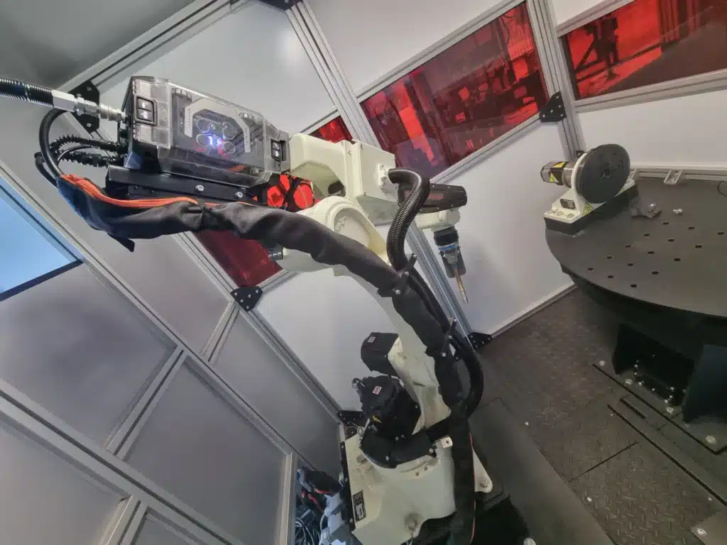 Bras robotisé Kawasaki en position de travail dans une cellule sécurisée.