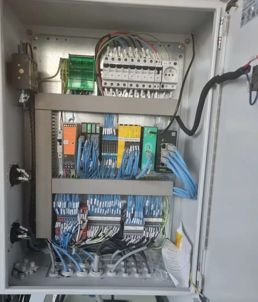 Vue intérieure d'une armoire de commande électrique avec rail DIN et disjoncteurs.