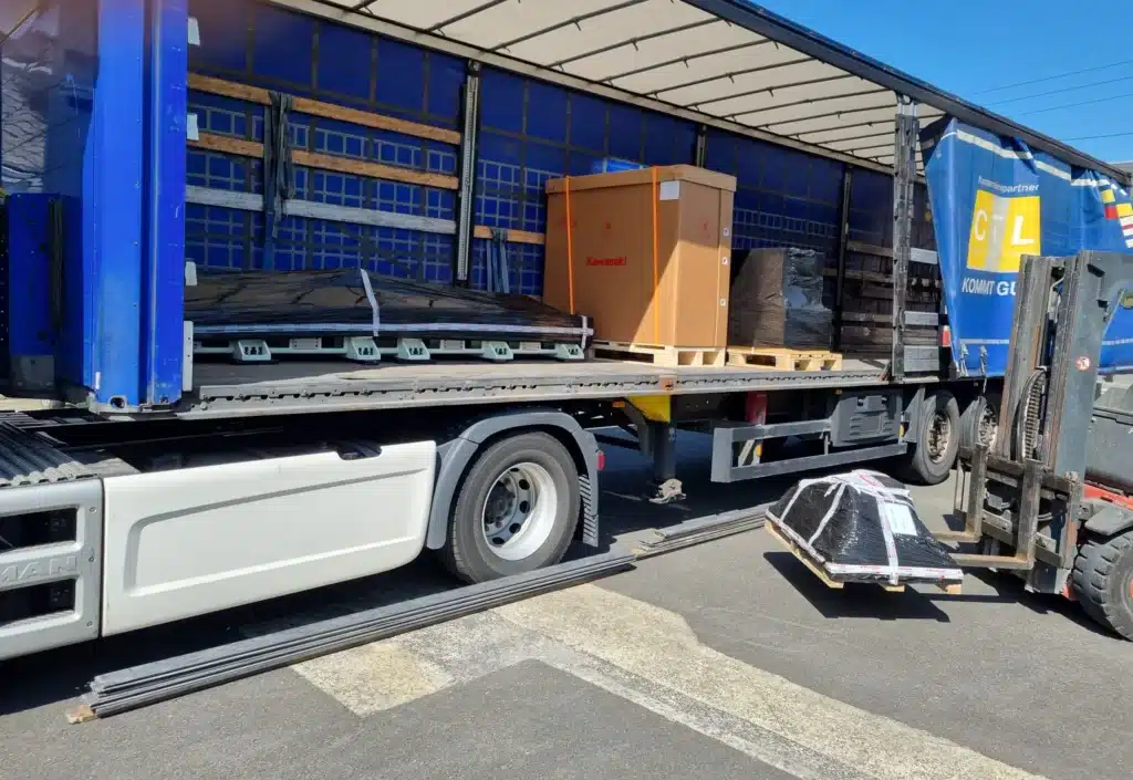 Chargement d'un camion avec des caisses d'équipements robotiques Kawasaki.