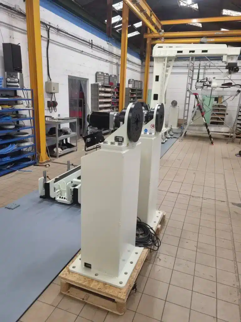 Colonnes de support blanches pour robots industriels en cours de montage en atelier.